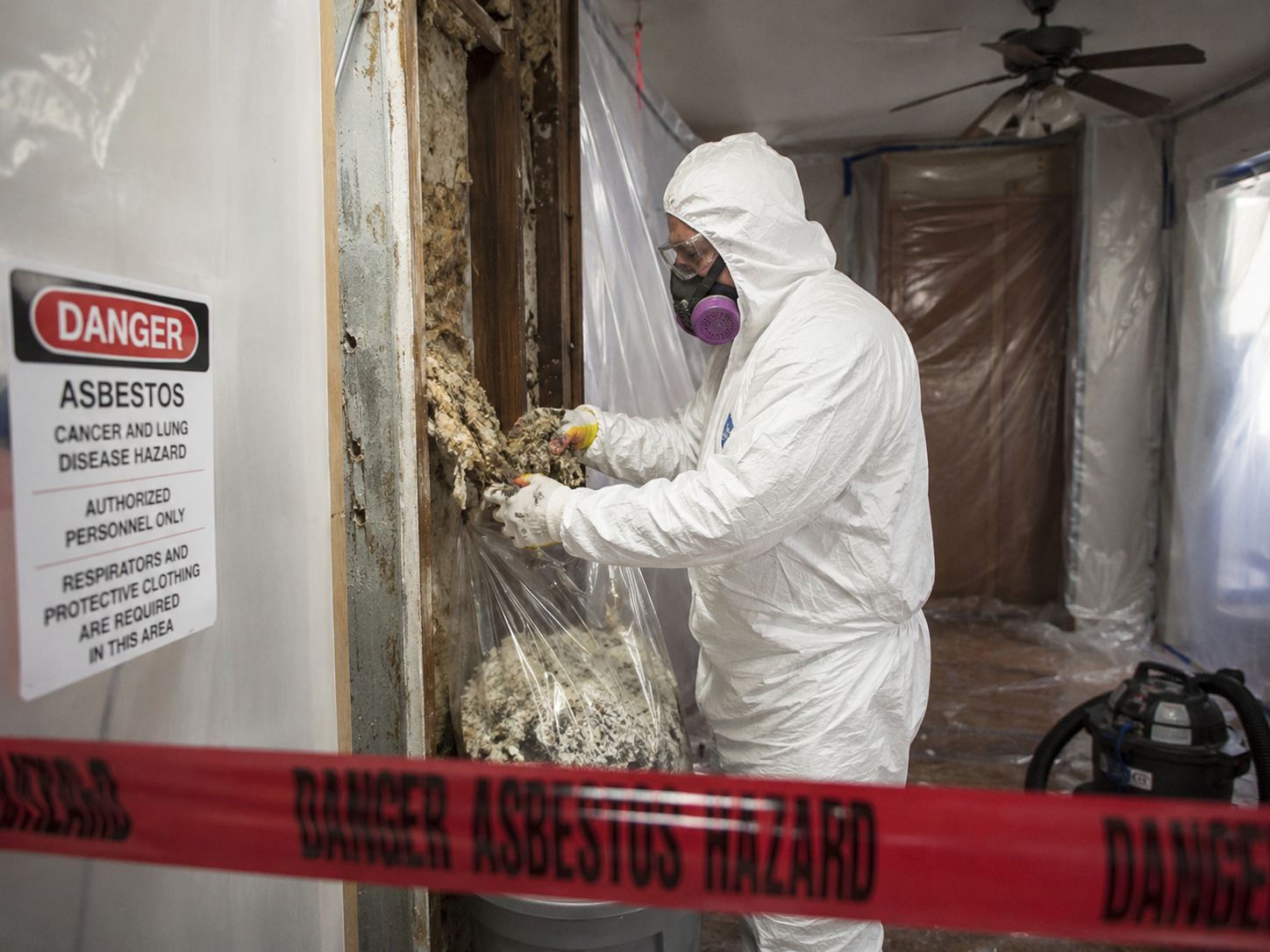 Asbestos removal specialist in protective gear removing asbestos materials